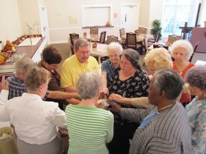 christmas-card-project-oct-2011-010 Widows Center director Coleman Peacock (in yellow) prays with the widows as they bless the cards and prayer cloths.