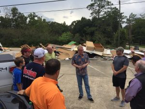 With debris from the flooded church behind them, General Overseer Tim Hill addresses congregants and volunteers at the Life Church. 
