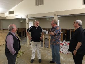 General Overseer Tim Hill, second from right,  speaks with Pastor David Doiron of the Savannah Branch church about flood damage to the church. Looking on is Secretary General John Childers (right) and Louisiana State Overseer Melvin Shuler. 