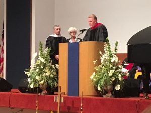General Overseer Tim Hill (at podium) performs the investiture of Pentecostal Theological Seminary President Michael Baker. Baker is joined by his wife, Sharon (click photo to enlarge). 